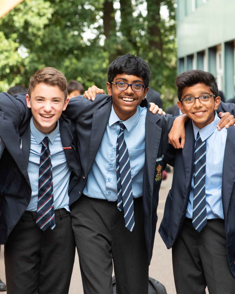 Three male students in a private school studying for their IGCSE Exams and hugging each other. They look happy
