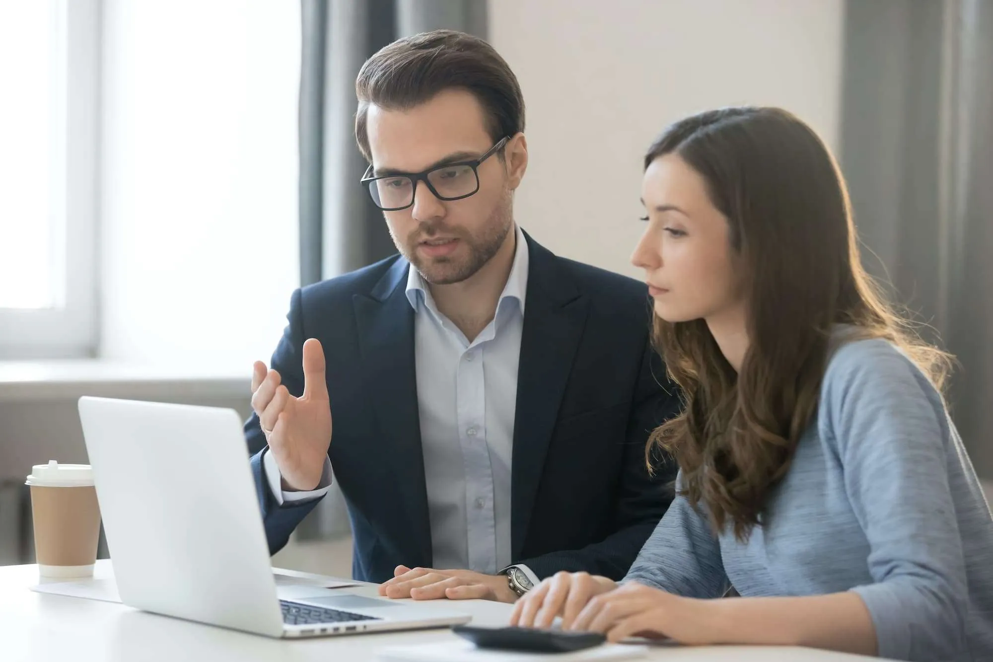 male teacher working with female teenage student on the computer and going through work